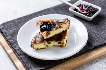 Cottage cheese casserole with berry jam on a white plate. Homemade casserole with cottage cheese and raisins.