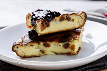 Cottage cheese casserole with berry jam on a white plate. Homemade casserole with cottage cheese and raisins.