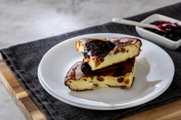 Cottage cheese casserole with berry jam on a white plate. Homemade casserole with cottage cheese and raisins.