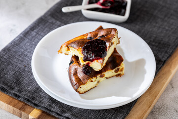 Cottage cheese casserole with berry jam on a white plate. Homemade casserole with cottage cheese and raisins.