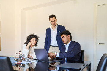 Lawyers working together on laptop in office meeting room
