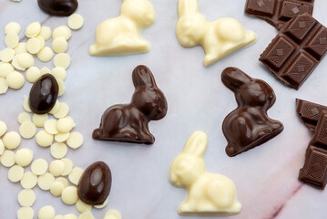 Dark and white chocolate Easter eggs and bunnies with fruit-colored candies and chocolate bars on a counter