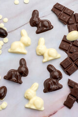 Dark and white chocolate Easter eggs and bunnies with fruit-colored candies and chocolate bars on a counter