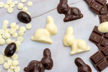 Dark and white chocolate Easter eggs and bunnies with fruit-colored candies and chocolate bars on a counter