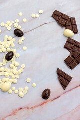 Dark and white chocolate Easter eggs and bunnies with fruit-colored candies and chocolate bars on a counter