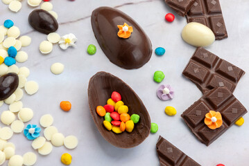 Dark and white chocolate Easter eggs and bunnies with fruit-colored candies and chocolate bars on a counter