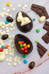 Dark and white chocolate Easter eggs and bunnies with fruit-colored candies and chocolate bars on a counter