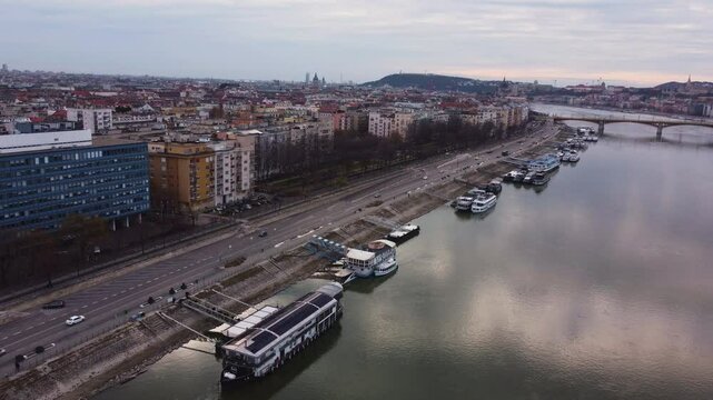 High angle of Budapest Danube River, boats, bridges, and urban landmarks, aerial pullback above ferries and water reflecting clouds, Pozsonyi Street, Margitsziget or margit hid bridge