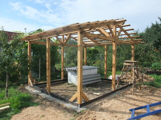 Building a wooden shelter in a garden location under a clear sky with tools and materials present