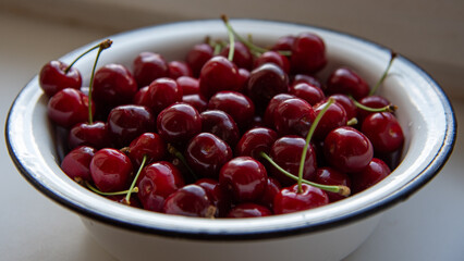 Sweet cherry close-up. Gorgeous red berries in white metal bowl. Glossy and juicy fruits gatgered from cherry tree. Garden harvest. Vegetarian food.