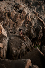 curly young fit female model pose on the rocky beach at Spain Andalucia