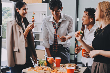 Asian office colleagues and friends enjoy a daytime BBQ with pizza and beer, celebrating Halloween and cheering for their favorite soccer team, creating a lively atmosphere filled with joy.