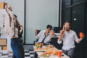 Asian office colleagues and friends enjoy a daytime BBQ with pizza and beer, celebrating Halloween and cheering for their favorite soccer team, creating a lively atmosphere filled with joy.