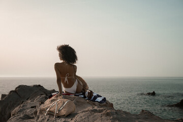 curly young fit female model pose on the rocky beach at Spain Andalucia