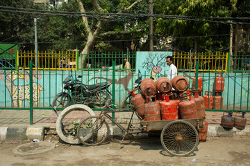 Fototapeta premium Indian and foreign people worker bike bicycle and use tricycle carrying and delivery gas product on the road of rural at Delhi city in New Delhi, India