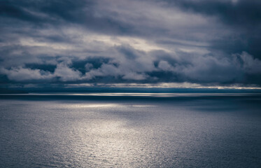 Dark, dramatic, moody storm clouds brewing over the calm Irish Sea, with sunlight breaking through, the Welsh coast, view from The Great Orme, Llandudno, North Wales, UK