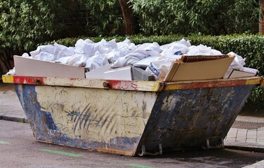 Contenedor de obra de la construcción lleno de sacos blancos y escombros