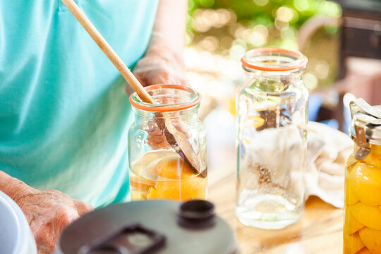 older woman preserving fresh fruit in canning jar