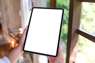 Mockup image of a woman holding tablet with blank desktop white screen at home