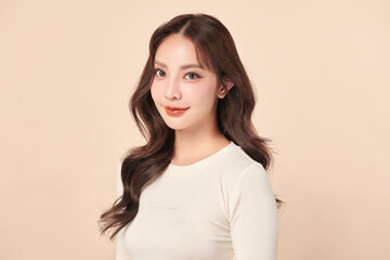 Obraz premium A beautiful young Asian woman with clean, fresh skin against a beige background. Skincare, facial treatment, cosmetology, beauty, and spa. An elegant portrait of an Asian woman.