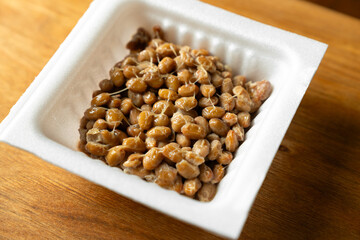 白いパック入りの納豆　木製テーブルの背景