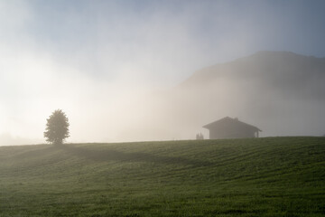 Foggy morning in the mountains with a house on the hill
