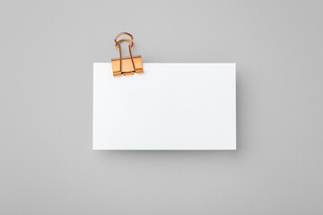 Copper binder clip with memo note paper on grey background