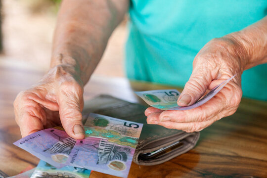 Old persons hands handing over australian bank notes