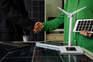 Businessmen shake hands after agreeing to start a new project successfully, renewable and sustainable development, and solar panel concept.