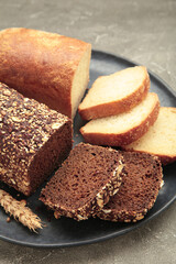 Different bread on plate on grey background. Vertical photo