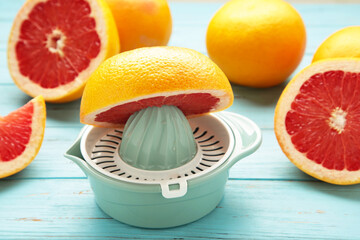 Juicer with freshly squeezed red grapefruit juice,with whole and sliced grapefruit on mint.