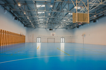 Empty sports hall with blue epoxy floor and volleyball net
