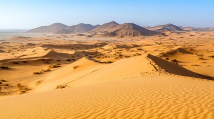 Panoramic view of vast desert landscape with sand dunes and distant mountains under clear sky.