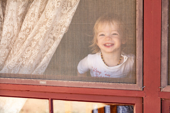Cheeky boy grinning out gauze window