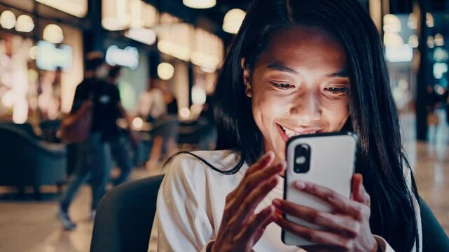 A young Asian woman or businesswoman using a smartphone cell in the city at night.