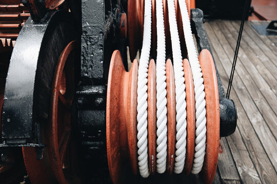 A series of white ropes wound around a large, red wheel or pulley at Old Whaling Station