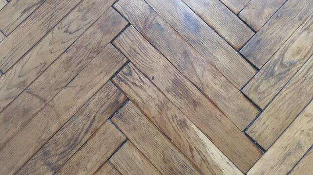 Texture of old worn herringbone parquet floor, requiring repair, close up	
