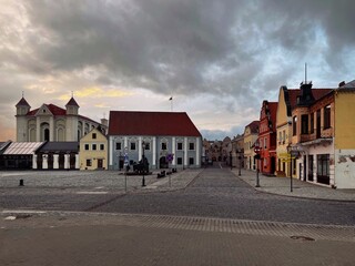 The old town of Kedainiai, Lithuania. A narrow street lined with historic buildings features a prominent yellow clock tower in the old town area.