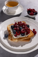 Toast with fresh blueberries, raspberries and red currants and ricotta cheese