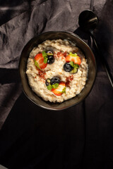 Oatmeal porridge with strawberries and blueberries and chia seeds on a black background