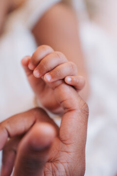 Newborn baby holding mother's finger close-up