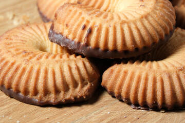 Delicious cookies with chocolate coating on a wooden surface