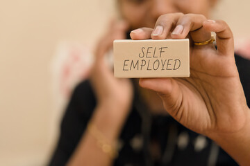 Holding a sign about self employment in a workspace