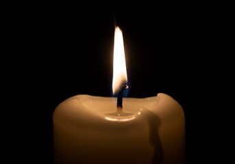 Single candle flame glows softly in dark background. AI Generated