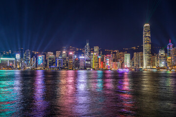 Fototapeta premium The night view Hong Kong skyline at night with lights and skyscrapers over sea with laser beams, lights show.