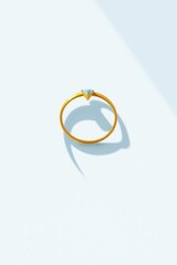 Gold ring with blue diamond minimalist design on subtle gradient background displaying soft shadows