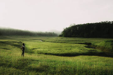 Fototapeta premium woman standing in landscaped view of a grassland