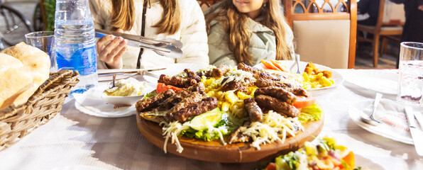 Platter of Grilled Meats and Vegetables Served on a Wooden Tray at a Dining Table