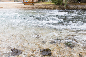 River Flowing Over Rocks With Wooden Structure And Greenery In Background