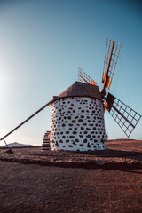 View of the old, typical windmills of Villaverde, Fuerteventura, Canary Islands, with their wooden blades. almost sunset, oblique light, golden hour. Past, vintage feeling.